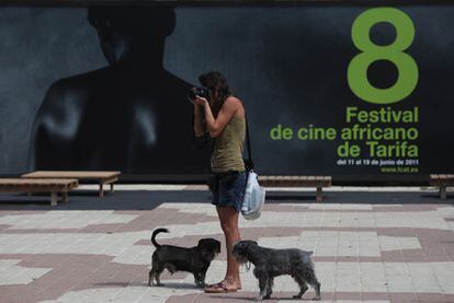 Una chica fotografía una exposición en las calles de Tarifa, al fondo el cartel del Festival de Cine Africano que comienza hoy.