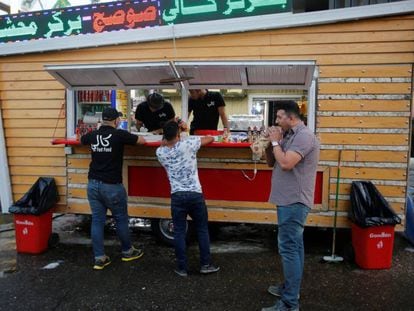 Tres iraqu&iacute;es junto a un restaurante callejero de Bagdad.