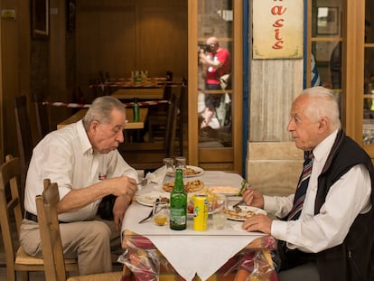 Dos hombres comen en una taberna.