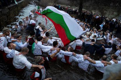 Varias personas bailan el tradicional "Horo" mientras ondean banderas búlgaras en las aguas heladas de un río durante las celebraciones de la Epifanía, en Kalofer, Bulgaria, este miércoles.