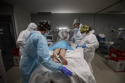 Varios sanitarios trabajan con un paciente infectado por coronavirus en estado muy grave, en una de las salas de UCI del Hospital Isabel Zendal de Madrid.