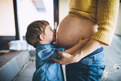 Un hijo abraza a su madre embarazada.