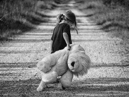 Una niña pasea triste con su oso peluche.