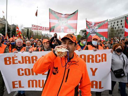 A man blows in a conch shell horn as demonstrators hold a banner and wave "Ikurrina" Basque flags during a demonstration called by farmers trade unions and hunting federations, forming a "Rural Alliance", to mark the economic and social importance of the rural sector and to demand "a future for the countryside", in Madrid on March 20, 2022. (Photo by Pierre-Philippe MARCOU / AFP)