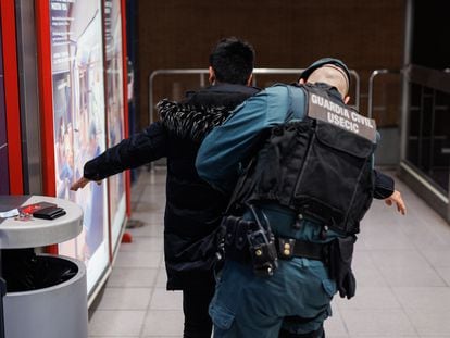Un agente de la Guardia Civil cachea a un joven en una estación de Metro, en febrero en Madrid.