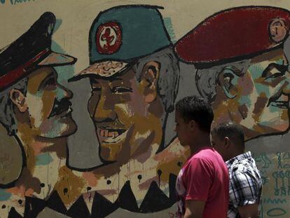 Dos transeúntes, ante un grafiti de miembros de la Junta Militar, en El Cairo.