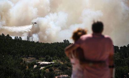 Una pareja contempla este miércoles cómo un helicóptero trabaja en las labores de extinción del incendio en el Algarve (Portugal).