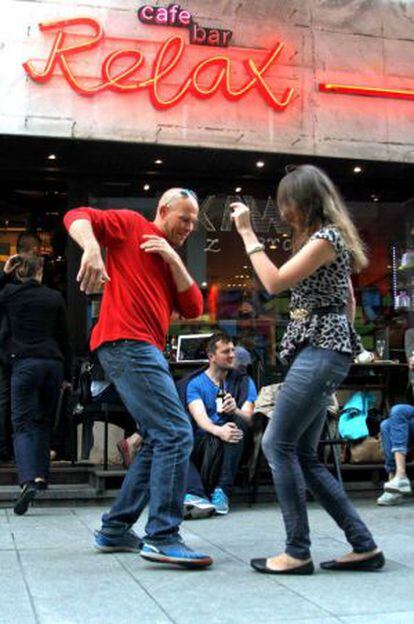 Dos personas bailan frente al café Relax de Varsovia.