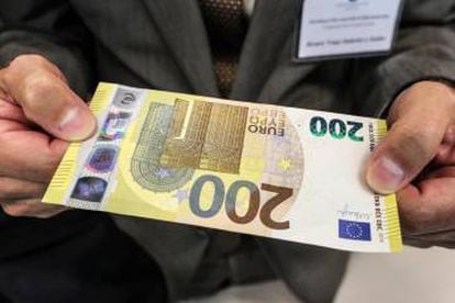 Un periodista sostiene el nuevo billete de 200 euros en la sede del BCE este lunes.