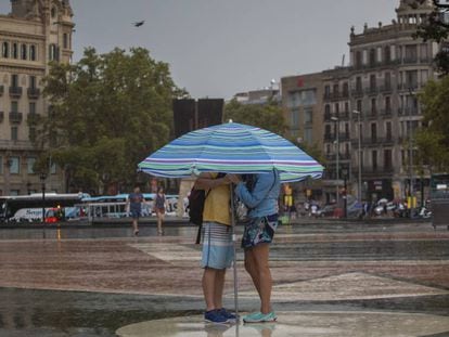 Una parella sota la pluja i sota un para-sol a la plaça de Catalunya.