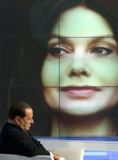 Silvio Berlusconi, con una imagen de su mujer al fondo.