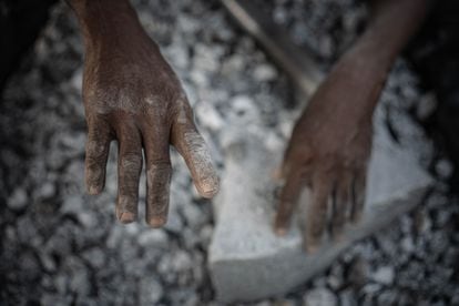 Brigitte shows her work-worn hands.  The granite stones are chipped with a steel bar, a task that causes serious injuries, especially in the case of miners who do not have any protection instrument for their workers.