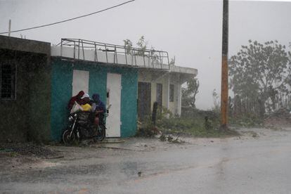 Una familia intenta protegerse de las fuertes lluvias durante el paso del huracán 'Fiona', en el municipio de Higüey. 