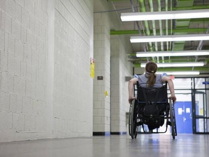 Una mujer en silla de ruedas en el pasillo de una institución educativa