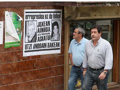 Los concejales Amutxastegi y Vela pasan frente a un cartel de apoyo a Barandiaran y Ozaeta.