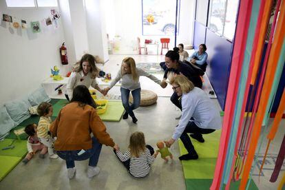Familiares y trabajadores juegan con niños en el Centro de la Casa Grande en el barrio de Tetuán en Madrid.
