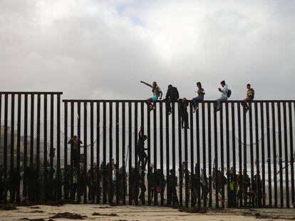 Migrantes encaramados a la valla que separa México de EE UU en San Diego (California), el 29 de abril. 