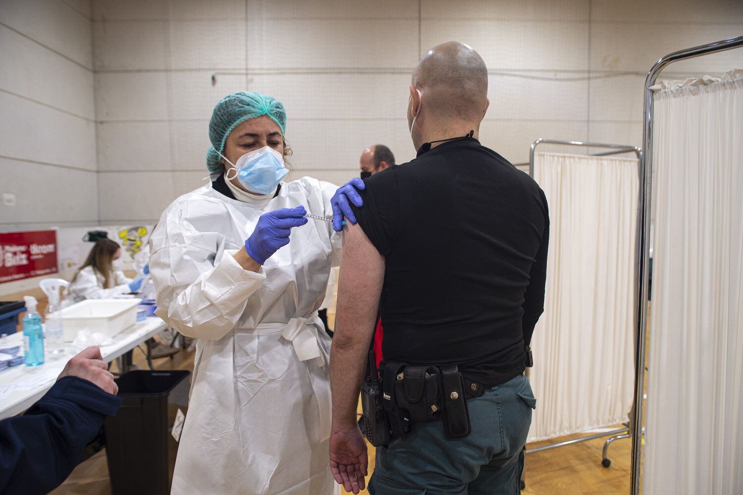 Una sanitaria suministra la vacuna de AstraZeneca a un agente de la Guardia Civil en el pabellón deportivo del Polígono Cabezo Beata de Cartagena,  Murcia, (España), el 9 de marzo.