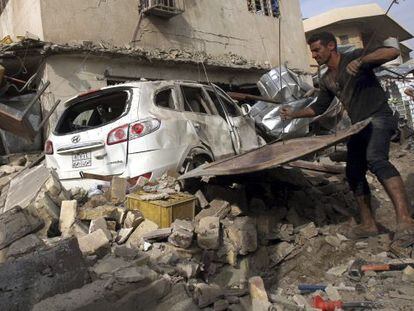 Un hombre quita escombros tras la explosi&oacute;n de un coche bomba en el barrio de Karada, en Bagdad, el pasado martes.
