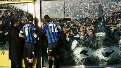 Jugadores del Atalanta tratan de calmar a los violentos, que rompieron las vallas y forzaron la suspensión de su partido con el Milan.