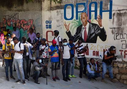 Un grupo de periodistas se reúne frente a un mural que muestra al presidente haitiano Jovenel Moïse, cerca de la residencia del líder, donde fue asesinado por hombres armados este miércoles 7 de julio.