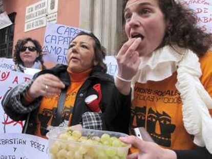 Trabajadoras de servicios sociales de la Diputación de Granada se toman las uvas con doce horas de antelación, justo al mediodía, para protestar por los despidos de 24 empleados y pedir que la asistencia social se mantenga como prioridad en la Administración provincial.