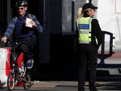 Un hombre cruza a Gibraltar subido en una bicicleta y muestra su pasaporte, este sábado.