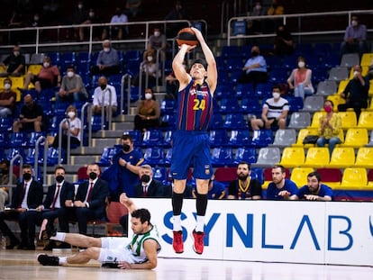 Kuric lanza un triple, con Bassas en el suelo, en el partido Barça-Joventut.