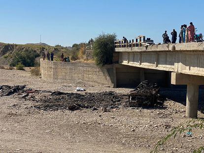 Un grupo de personas observa los restos del autobús que este domingo ha caído por un puente en el distrito de Lasbela, en Pakistán.