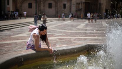 Una mujer se refresca en una fuente del centro histórico de Valencia.