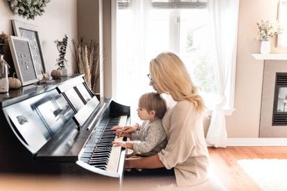 Un niño toca el piano con su madre.