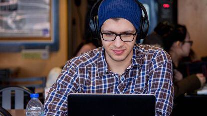 Un joven practica inglés con su ordenador en una cafetería.