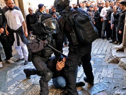 Dos agentes israelíes inmovilizan a un hombre palestino en la entrada del recinto de la mezquita de al-Aqsa mientras se impide el ingreso de otros, este viernes.