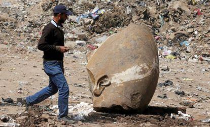Un hombre pasa junto a la cabeza de la estatua hallada este jueves en una excavación en El Cairo.