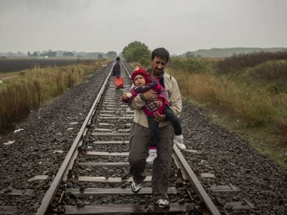 Un padre camina por las vías del tren con su hijo en brazos después de cruzar la frontera entre Serbia y Hungría (Roszke, Hungría, septiembre de 2015).