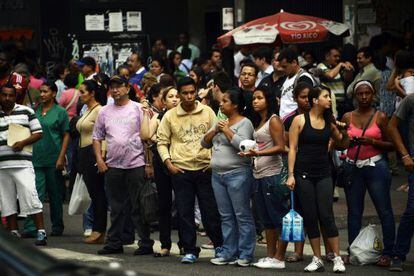Personas esperan por el transporte público esta tarde en una calle de Caracas.