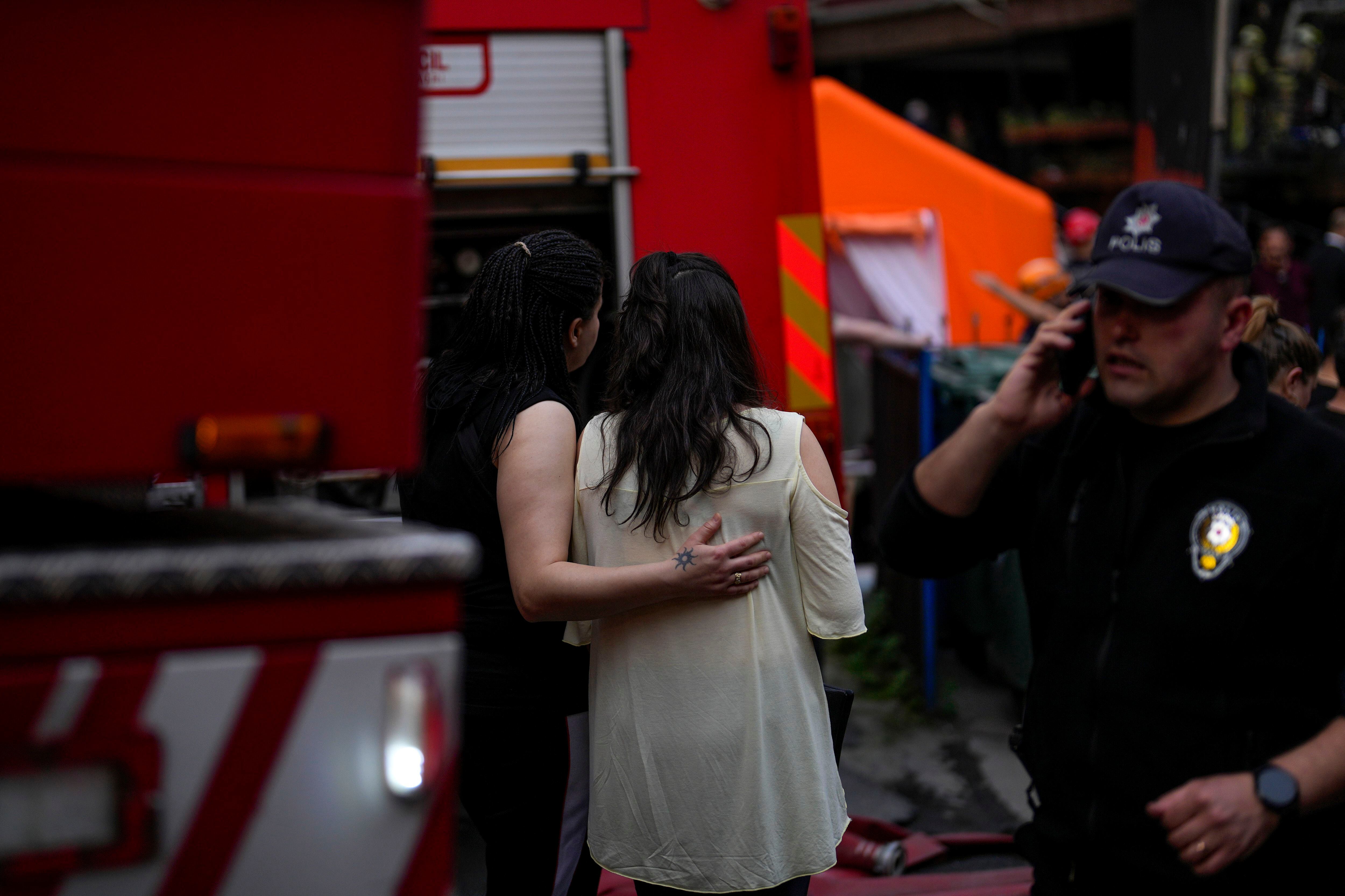 Dos mujeres se lamentan, mientras los bomberos y los servicios de emergencia trabajan en la zona afectada, este martes en Estambul. 
