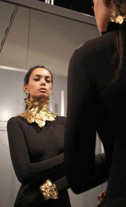 Una modelo se mira al espejo en las pruebas antes del desfile.