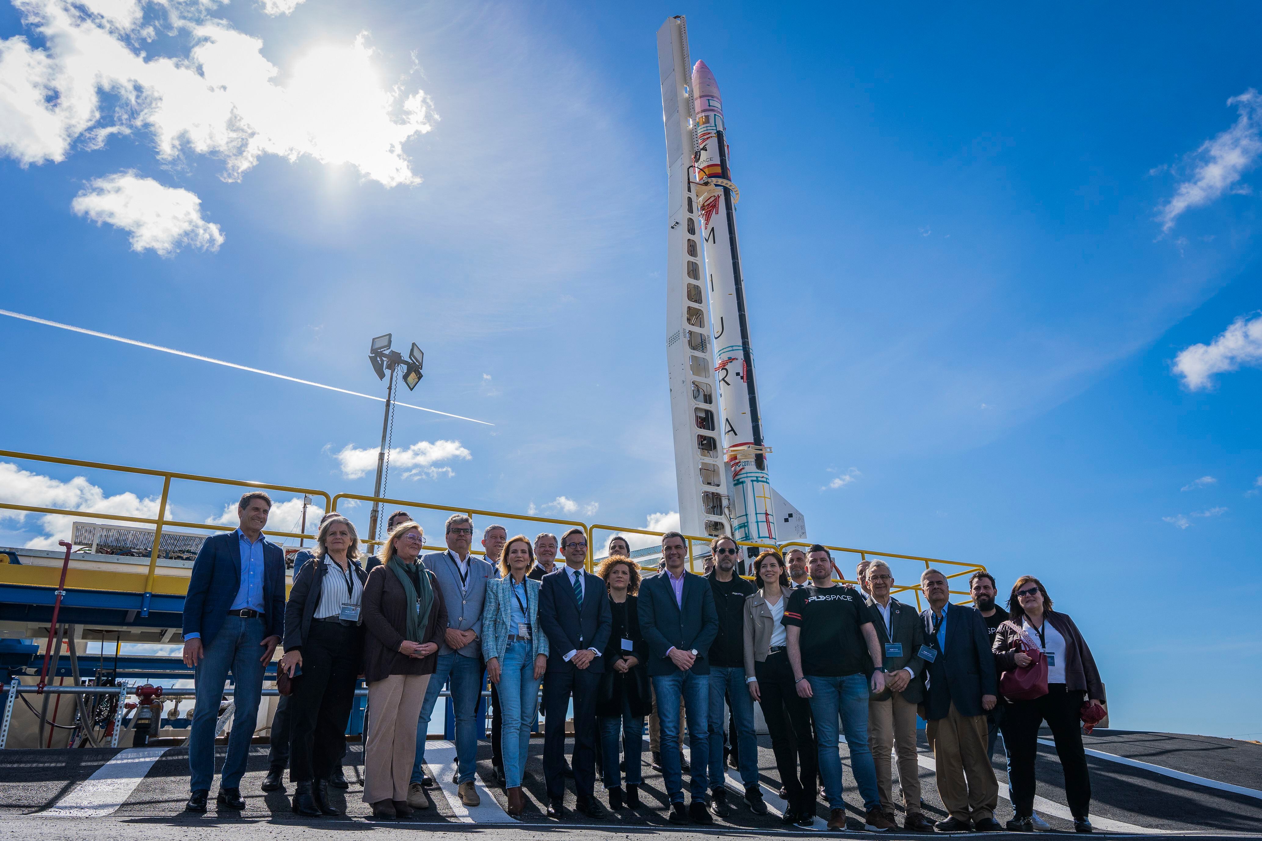 El presidente del Gobierno, Pedro Sánchez, y otras autoridades y responsables de PDL Space, posan ante la plataforma del cohete privado 'Miura-1'.