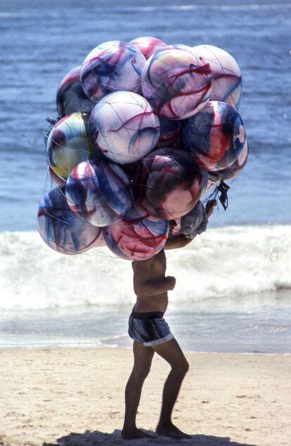 Los globos tapan a este vendedor en una playa de Río. "Voy por la calle y voy vendido. Voy tropezando solo de ver la gente. Me vuelvo a mirar la gente y me digo ¡me cago en la mar! ¡qué foto he perdido!", comentaba en el documental 'Afal, una mirada libre' sobre el grupo fotográfico almeriense.