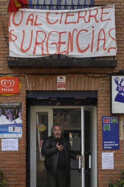 Un vecino sale de una tienda con una pancarta en defensa de las urgencias de Chiloeches.
