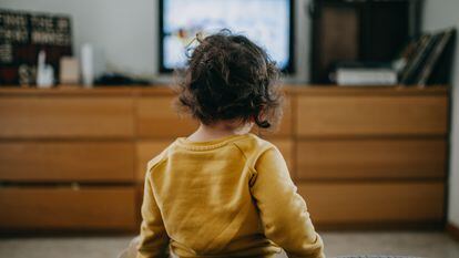 Una niña ve la televisión tradicional en casa.