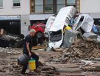 Bad Neuenahr-ahrweiler (Germany), 16/07/2021.- A person carrying buckets walk amid debris near a pile of damaged cars after flooding in Bad Neuenahr-Ahrweiler, Germany, 16 July 2021. Large parts of Western Germany were hit by heavy, continuous rain in the night to 15 July resulting in local flash floods that destroyed buildings and swept away cars. (Inundaciones, Alemania) EFE/EPA/FRIEDEMANN VOGEL