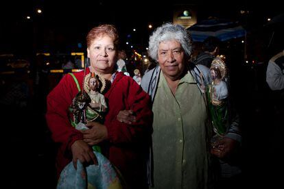 Dos fieles de San Judas posan con sus figuras del santo durante el culto del pasado jueves en la iglesia de San Hipólito.