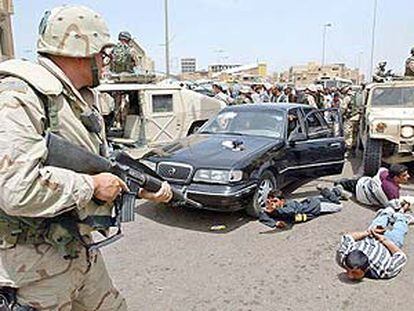 Un policía militar estadounidense apunta con su arma a iraquíes detenidos por saqueo en el centro de Bagdad.