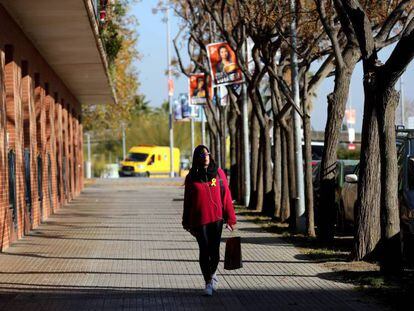 Una mujer con lazo amarillo pasea bajo carteles de C's.