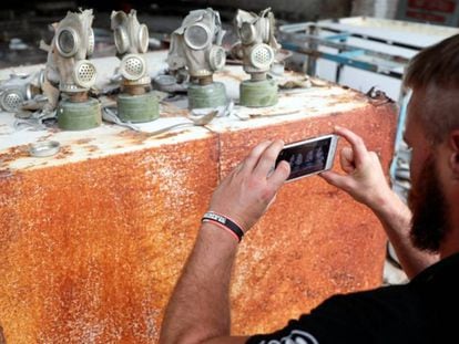 Un visitante toma una fotografía de máscaras antigás en una antigua base del ejército soviético, cerca de la Central Nuclear de Chernóbil.