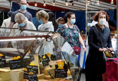 Varias personas hacen la compra en un mercado al aire libre de París.