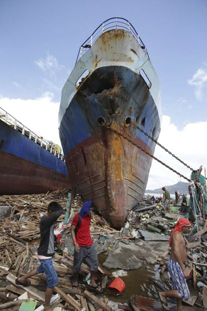 Varios supervivientes al pie de un gran barco desplazado por las fuertes olas fuera del agua, causados ​​por el poderoso tifón Yolanda en Tacloban City, provincia de Leyte