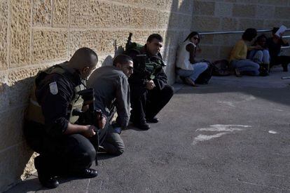 Policías y civiles se refugian en un muro tras la alerta en Jerusalén por el lanzamiento de un cohete desde Gaza.